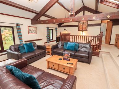 A sitting area with three brown leather sofas and blue cushions at Old Coach House Ambleside