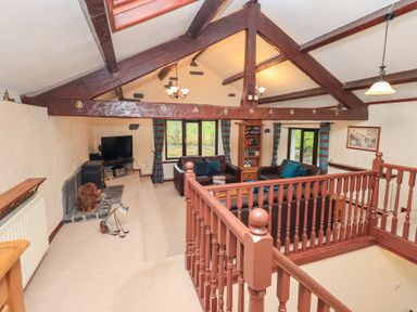 A living room with exposed wooden beams a television and leather sofas at Old Coach House in Ambleside