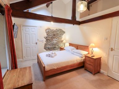 A bedroom with a wooden bed and bedside tables with lamps at Old Coach House Ambleside