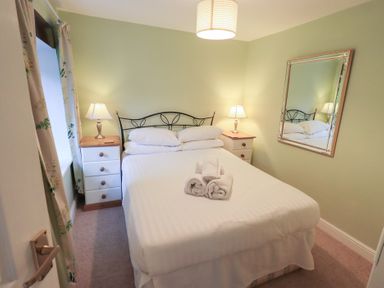A bedroom with a double bed two bedside tables with lamps and a wall mirror at Old Coach House Ambleside