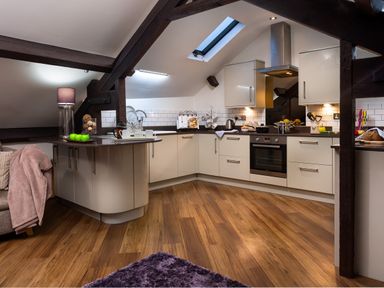 A kitchen with white cabinets wooden floor and skylight at Hayloft in Windermere