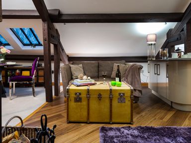 A living area with a sofa a yellow trunk used as a coffee table and a dining table with a purple chair at Hayloft in Windermere