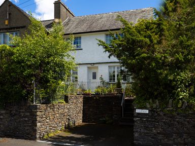 A white two story house with a stone wall and greenery at Uldale in Ambleside