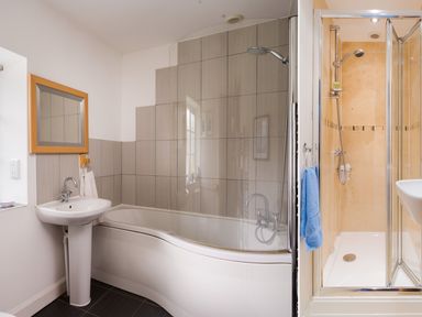A bathroom with a bathtub and shower on the left and a separate enclosed shower with glass doors on the right at Uldale in Ambleside