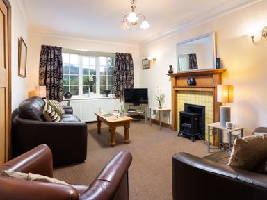 A living room with leather sofas a wooden coffee table a fireplace and a television at Uldale in Ambleside