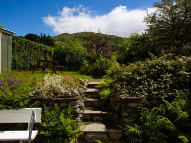 A garden with stone steps surrounded by plants a bench and a picnic table at Uldale in Ambleside