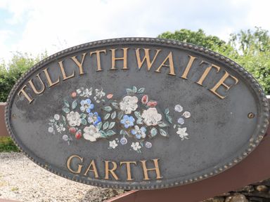 An oval metal sign with floral design and the words Tullythwaite Garth in Crosthwaite