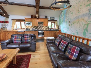 A kitchen and living area with brown leather sofas and plaid pillows at Tullythwaite Garth in Crosthwaite