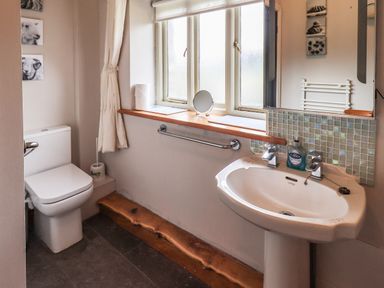 A bathroom with a toilet sink mirror and window at Tullythwaite Garth in Crosthwaite
