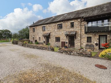 Stone residential building with multiple doors and windows and gravel driveway at Tullythwaite Garth in Crosthwaite