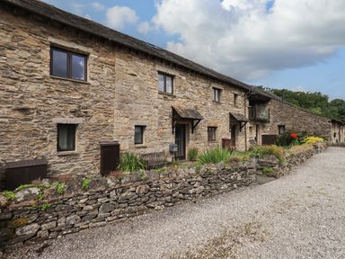 A row of stone cottages with a gravel path and low stone wall in front at Tullythwaite Garth in Crosthwaite