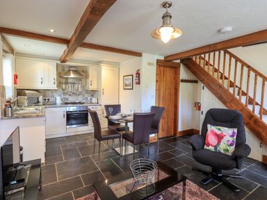A kitchen and dining area with tiled floor and wooden beams at Bobbin Cottage in Ings