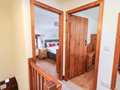 View of a wooden staircase landing with two doorways leading to bedrooms at Bobbin Cottage in Ings