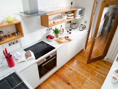 A kitchen with a stove oven countertop wooden shelves and a glass door at The Stable At Oakbank in Elterwater