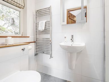 A bathroom with a toilet sink towel rack and mirror at The Stable At Oakbank in Elterwater