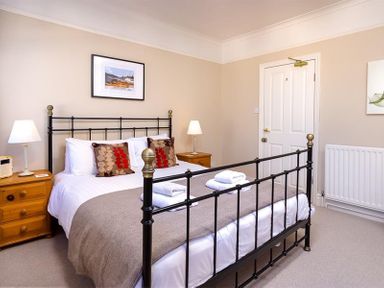 A bedroom with a black metal bed frame two bedside tables with lamps and folded towels at Highbank in Bowness