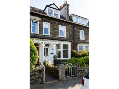 A stone house with white framed windows and doors with a red door beside it at Highbank in Bowness