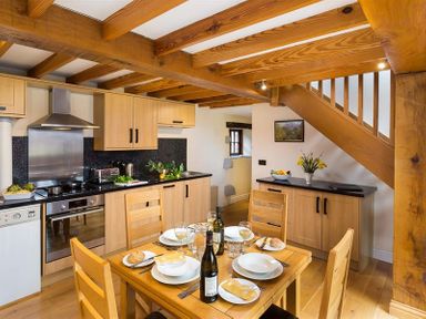 A kitchen with dining table and wooden beams at Nest Barn in Keswick