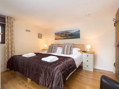 A bedroom with a double bed and bedside tables with lamps at Nest Barn in Keswick
