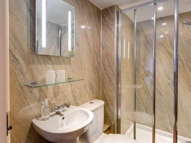 A bathroom with a sink toilet mirror glass shelf and shower enclosure at Nest Barn in Keswick