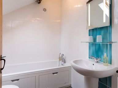 A bathroom with a bathtub a sink a mirror and a liquid soap dispenser at Nest Barn in Keswick