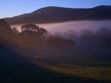 A landscape with hills trees and mist in the early morning at Nest Barn in Keswick
