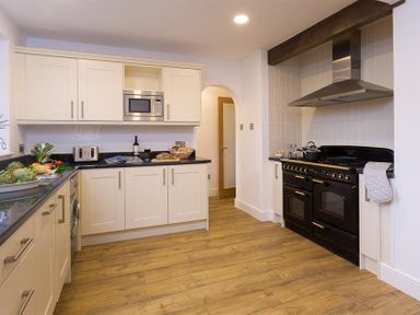 A kitchen with white cabinets a black stove and a microwave at Lanterns At Grasmere in Grasmere