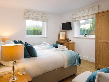 A bedroom with two single beds side by side with blue cushions and blanket at Lanterns At Grasmere in Grasmere