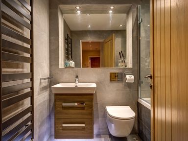 A bathroom with a sink cabinet a wall-mounted toilet a large mirror and a heated towel rail at Hart Head Barn in Rydal