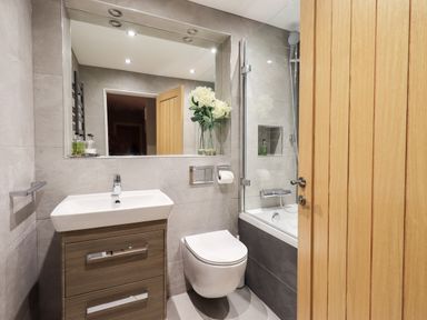 A bathroom with a sink cabinet toilet bathtub and mirror at Hart Head Barn in Rydal