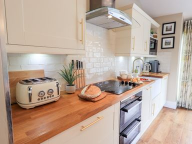 A kitchen with wooden countertops a bread loaf toaster stovetop and kettle at Hart Head Barn in Rydal