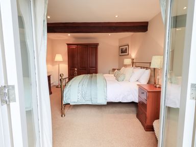 A bedroom with a metal bed frame wooden wardrobe bedside table and lamps at Hart Head Barn in Rydal