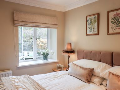 A bedroom with a bed pillows a lamp and framed botanical prints at Hart Head Barn in Rydal