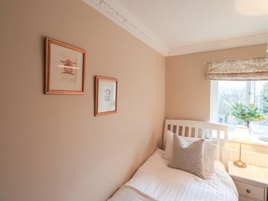 A bedroom with a bed pillow lamp and framed pictures on the wall at Hart Head Barn in Rydal