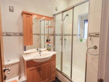 A bathroom with a wooden vanity sink cabinet a toilet and a glass shower enclosure at Hart Head Barn in Rydal