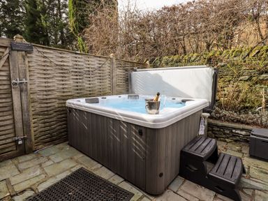 An outdoor hot tub with steps and a champagne bottle in an ice bucket at Hart Head Barn in Rydal
