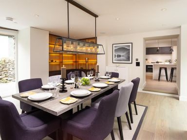 A dining room with a set table and six purple chairs at Underhowe in Grasmere