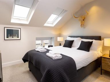 A bedroom with a double bed two skylight windows bedside lamps and a wall decoration at Underhowe in Grasmere