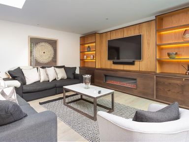 A living room with a large wall mounted television and built in shelves at Underhowe in Grasmere