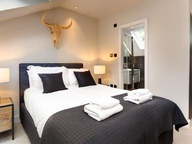 A bedroom with a bed and black pillows and a bull skull on the wall at Underhowe in Grasmere