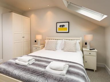 A bedroom with a double bed two bedside tables lamps a wardrobe and a skylight window at Underhowe in Grasmere