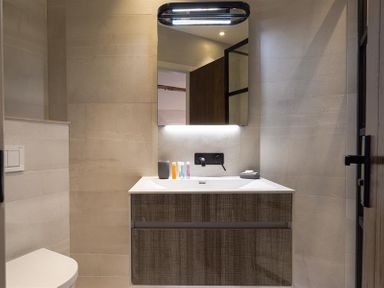 A bathroom with a wall-mounted vanity and mirror above the sink at Underhowe in Grasmere
