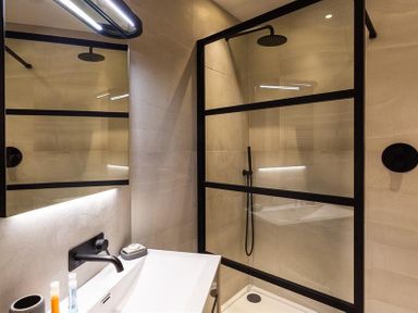 A bathroom with a sink and a shower area with black framed glass panels at Underhowe in Grasmere