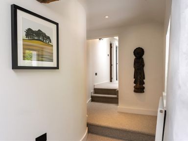 A hallway with carpeted steps a framed picture on the wall and a wooden sculpture at Underhowe in Grasmere