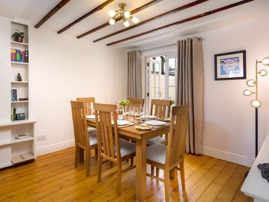 A dining room with a wooden table set for six people near glass doors at Hill Cottage Ambleside