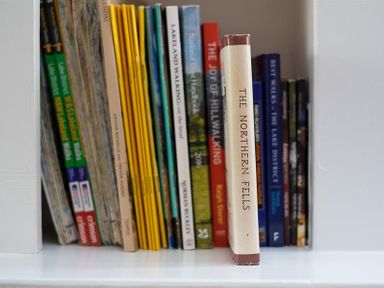 A shelf with a collection of books and magazines including The Northern Fells and Lakeland Walking at Hill Cottage in Ambleside