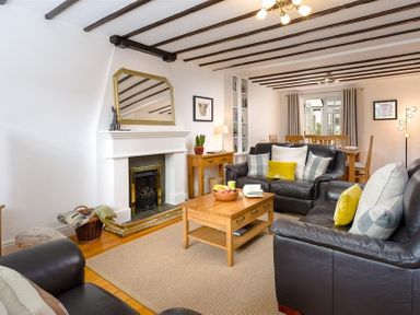 A living room with black leather sofas wooden coffee table fireplace and dining table at Hill Cottage in Ambleside