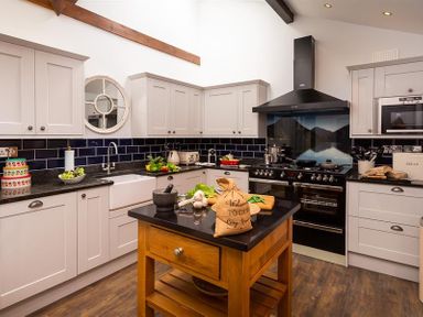 A kitchen with white cabinets black countertops and a wooden island at Ellerthwaite House in Windermere