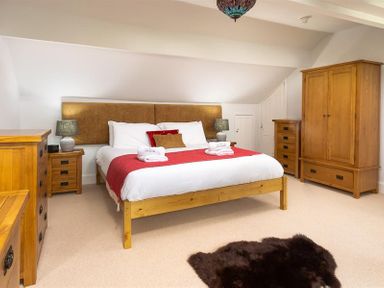 A bedroom with a large bed with white and red bedding wooden furniture and a dark rug on the floor at Ellerthwaite House in Windermere