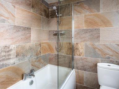 A bathroom with a bathtub shower combination and a toilet at Ellerthwaite House in Windermere